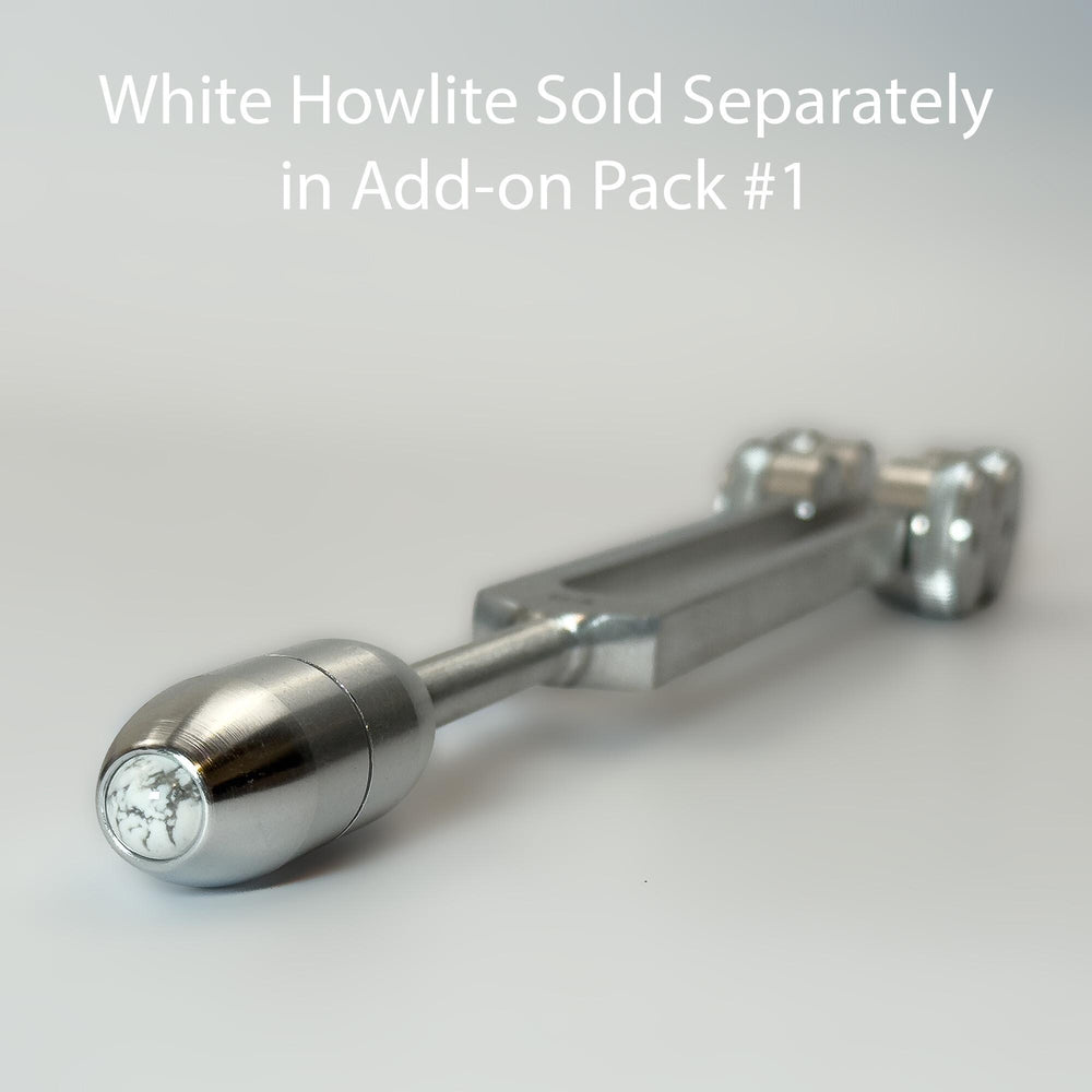 A close-up view of a silver-colored metal object, possibly a tool or device, with a text overlay that reads "White Howlite Sold Separately in Add-on Pack #1".