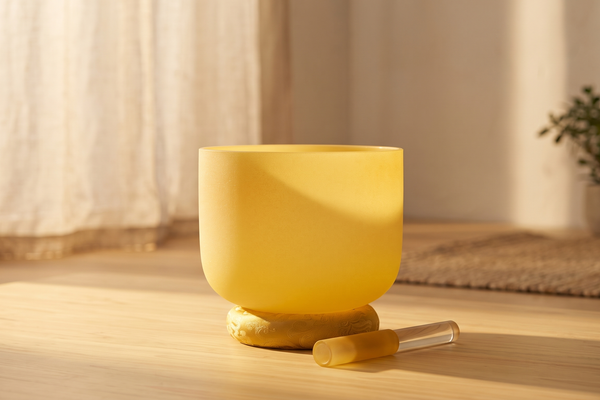 Yellow crystal singing bowl on a gold cushion in a warm morning meditation setting