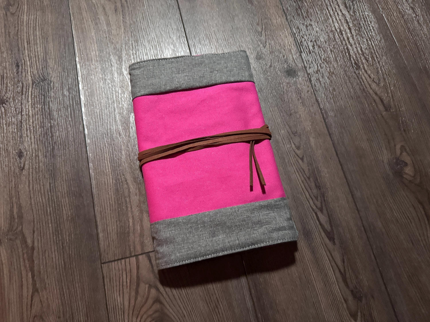 a pink and grey notebook on a wooden floor