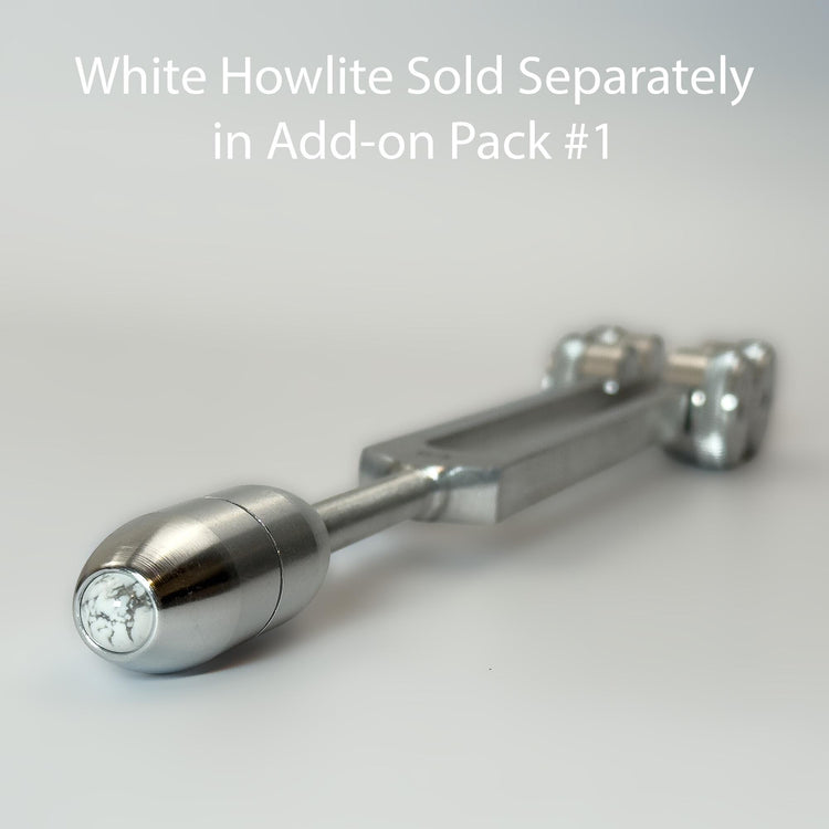 A close-up view of a silver-colored metal object, possibly a tool or device, with a text overlay that reads &quot;White Howlite Sold Separately in Add-on Pack #1&quot;.