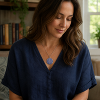 Indigo and silver Flower of Life charm necklace worn with a blue linen top